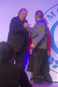 Earl Teats shaking hands with company co-founder Richard O'Brien on stage